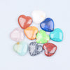 A collection of heart-shaped amethyst crystal stones in various colors including pink, orange, blue, and green.