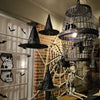 Classic black witch hats with hanging rope used as Halloween décor against a brick wall.