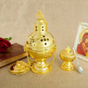 A gold-plated Orthodox censer with bells resting on a beige cloth next to a small spoon.