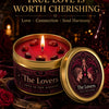 A candle labeled The Lovers Tarot Candle in orange blossom vanilla set against a dark, romantic background.