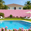A pink artificial cherry blossom privacy fence screen in front of a house and swimming pool.