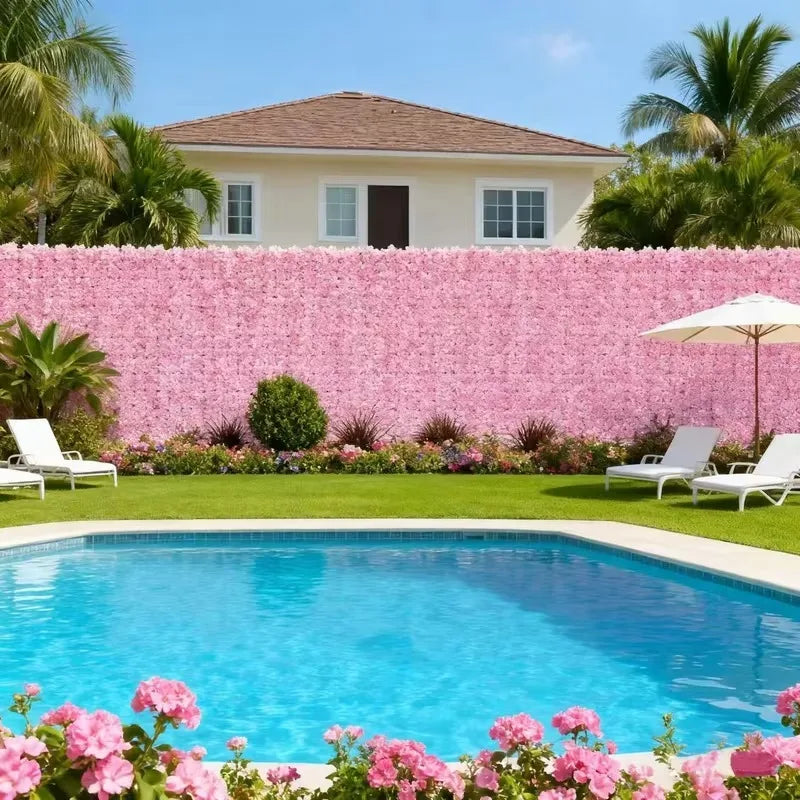 A pink artificial cherry blossom privacy fence screen in front of a house and swimming pool.