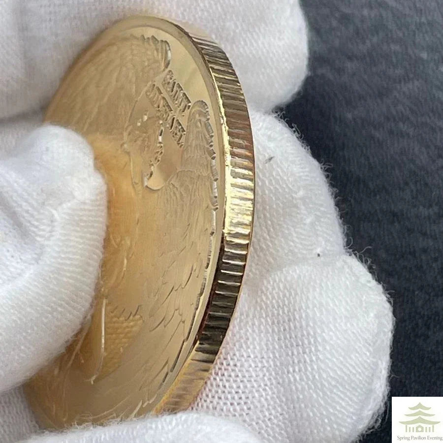 A gold souvenir coin is held in a white glove against a dark background.