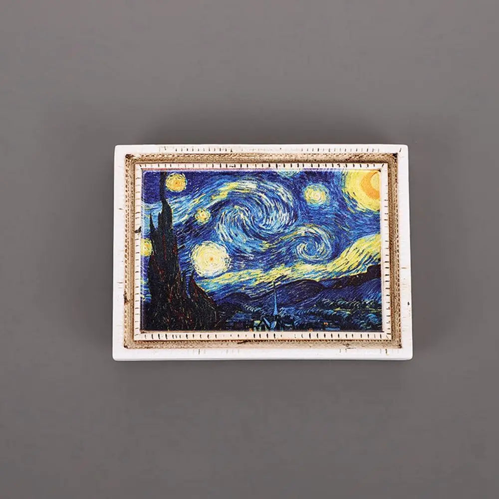 A framed painting depicting a night sky with stars and a silhouette of a cypress tree in blue and yellow tones.