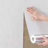 Une main décolle un rouleau d'autocollants waterproof en 3D de couleur blanche de leur papier de support.