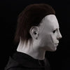 A realistic horror animal mask with dark hair and pale skin is shown in profile against a black background.