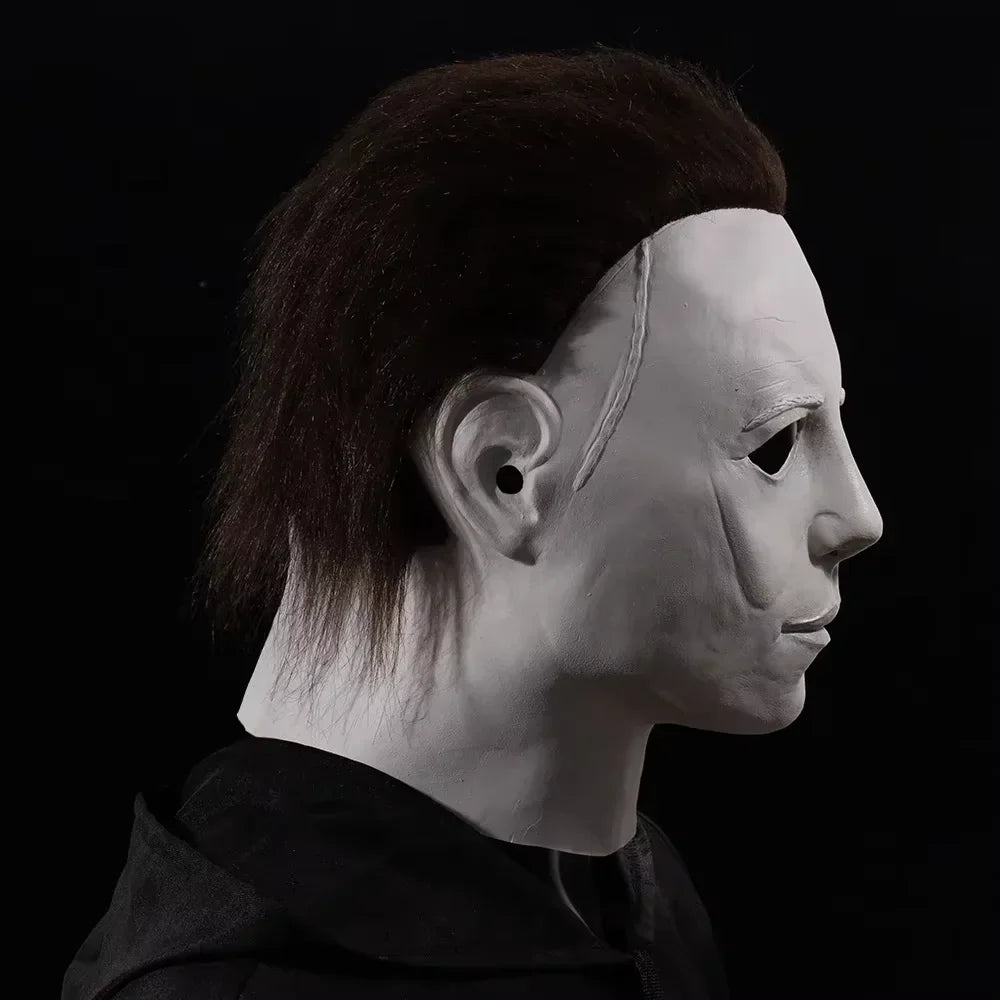 A realistic horror animal mask with dark hair and pale skin is shown in profile against a black background.