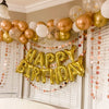 A golden balloon arch decoration featuring gold and white balloons for a birthday party.