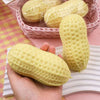 A hand holds a yellow peanut-shaped stress ball with a textured surface, resting on a pink woven basket and white surface.