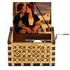 A carved wooden music box featuring a scene of two people kissing, set in a decorative wooden box.