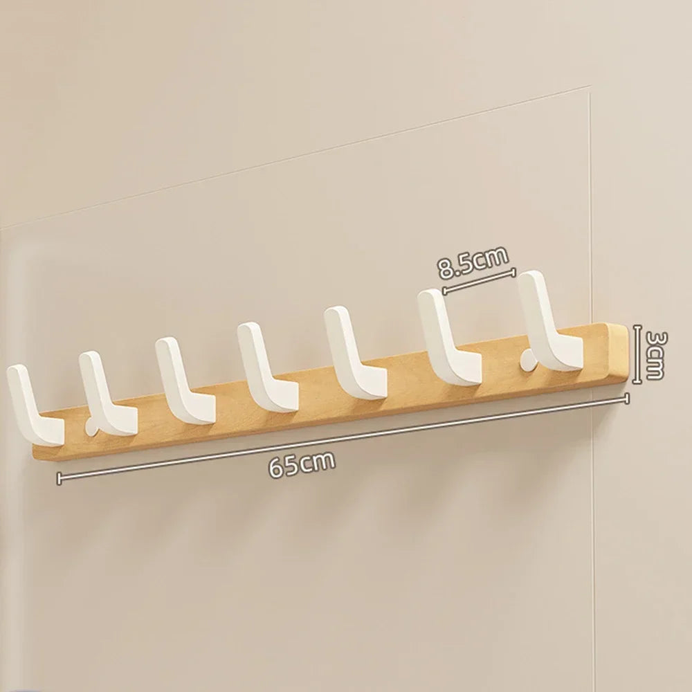A walnut wood coat rack with eight white hooks and a storage shelf mounted on a light wall.