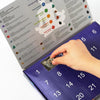 A close-up of a Christmas advent calendar featuring natural crystal gemstones and astrological symbols.
