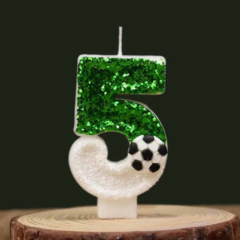A decorative candle shaped like the number 5, covered in green glitter, with a soccer ball detail on the bottom.