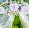 A floral archway decorated with light pink paper folding fans and greenery for an event backdrop.