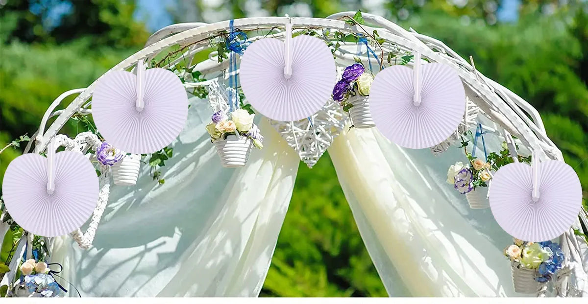 A floral archway decorated with light pink paper folding fans and greenery for an event backdrop.