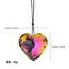 A faceted pink and yellow crystal heart pendant hanging from a black cord.