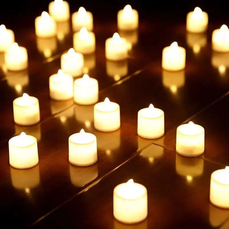 A row of glowing white LED tea light candles arranged on a dark reflective surface.