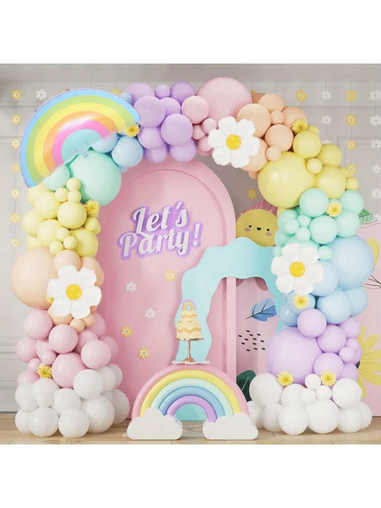A pastel rainbow balloon arch kit featuring pink, purple, and light blue balloons with flowers and clouds for party decoratio