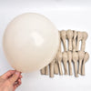 A large, smooth beige balloon is shown next to a bundle of elongated, pale beige balloons.