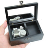 A hand-cranked wooden music box with an open lid showing the internal mechanism.