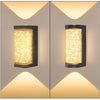A pair of modern LED crystal outdoor wall sconces with a warm yellow light mounted on a light gray wall.