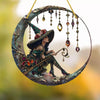 A decorative hanging witch hat and staff made of stained glass, featuring green and purple hues.