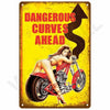 Vintage-Metallwandtafel mit Frau auf Motorrad, Text "DANGEROUS CURVES AHEAD" auf gelbem Hintergrund.