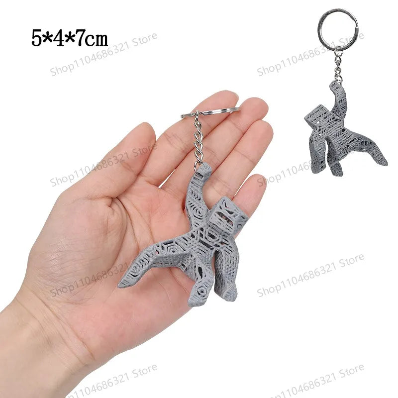 A silver-colored collectible figurine of Rocky and Grace, shaped like starfish, being held in a hand.