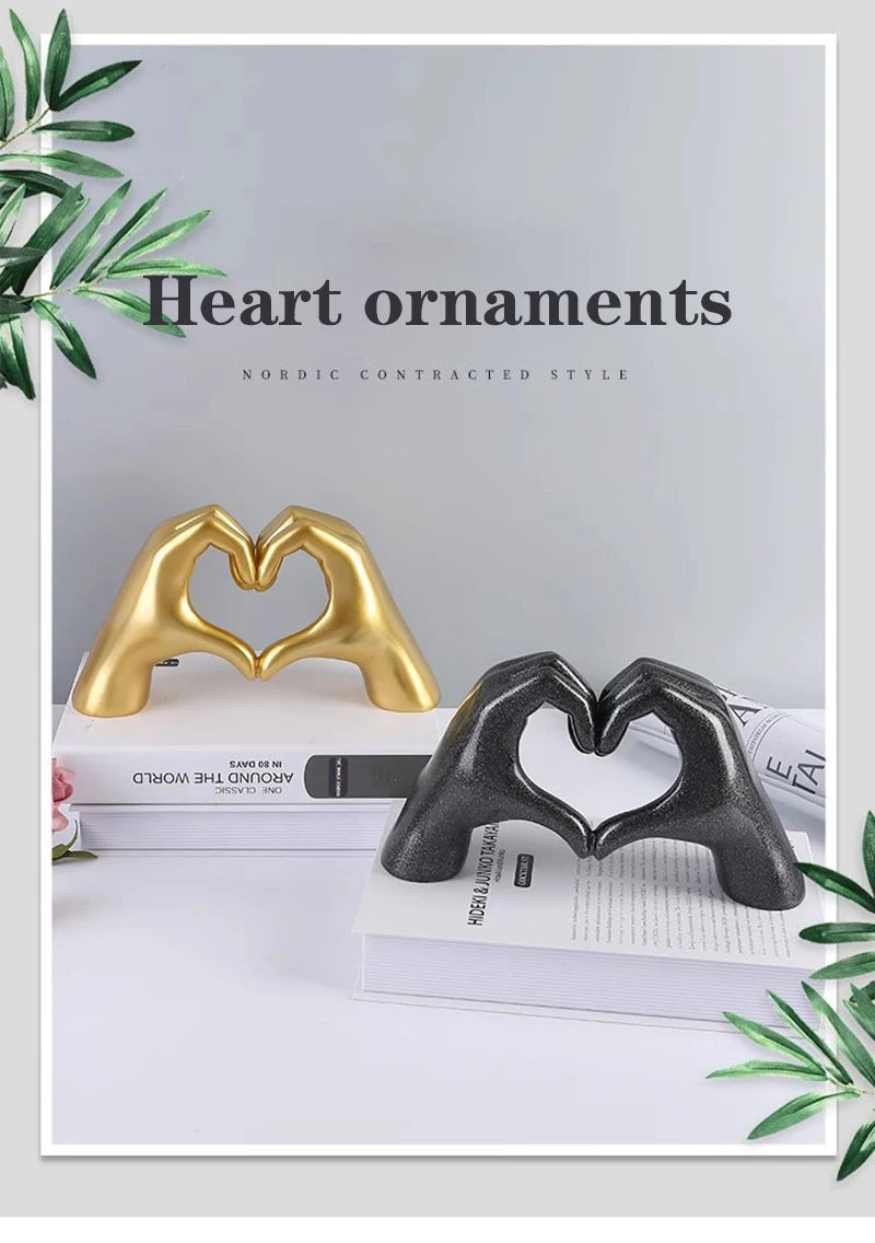 Gold and black heart-shaped resin hand sculptures used as decorative ornaments on a white surface.