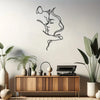Minimalist metal silhouette art of a cat and woman against a light gray wall above a wooden cabinet.