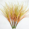 A bundle of artificial grass greenery with thin, straw-like blades in shades of yellow and orange.