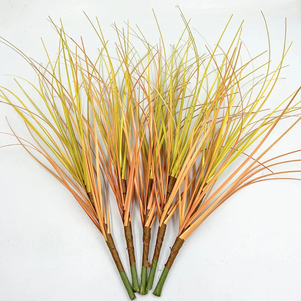 A bundle of artificial grass greenery with thin, straw-like blades in shades of yellow and orange.