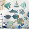 A collection of ten wooden, teal and blue fish shapes are displayed against a white wall.