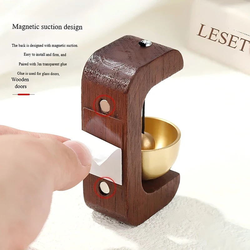 A wooden doorbell with a magnetic suction design is shown being installed on a white surface.