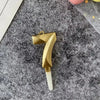 A gold 3D crown number cake candle for birthdays and celebrations is shown against a gray textured background.