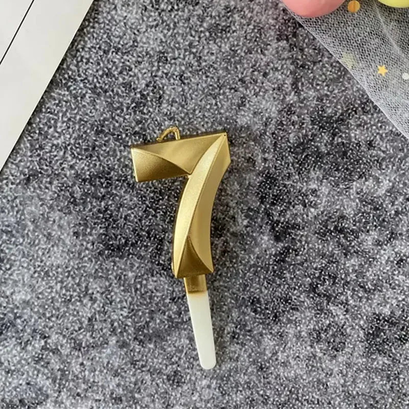 A gold 3D crown number cake candle for birthdays and celebrations is shown against a gray textured background.
