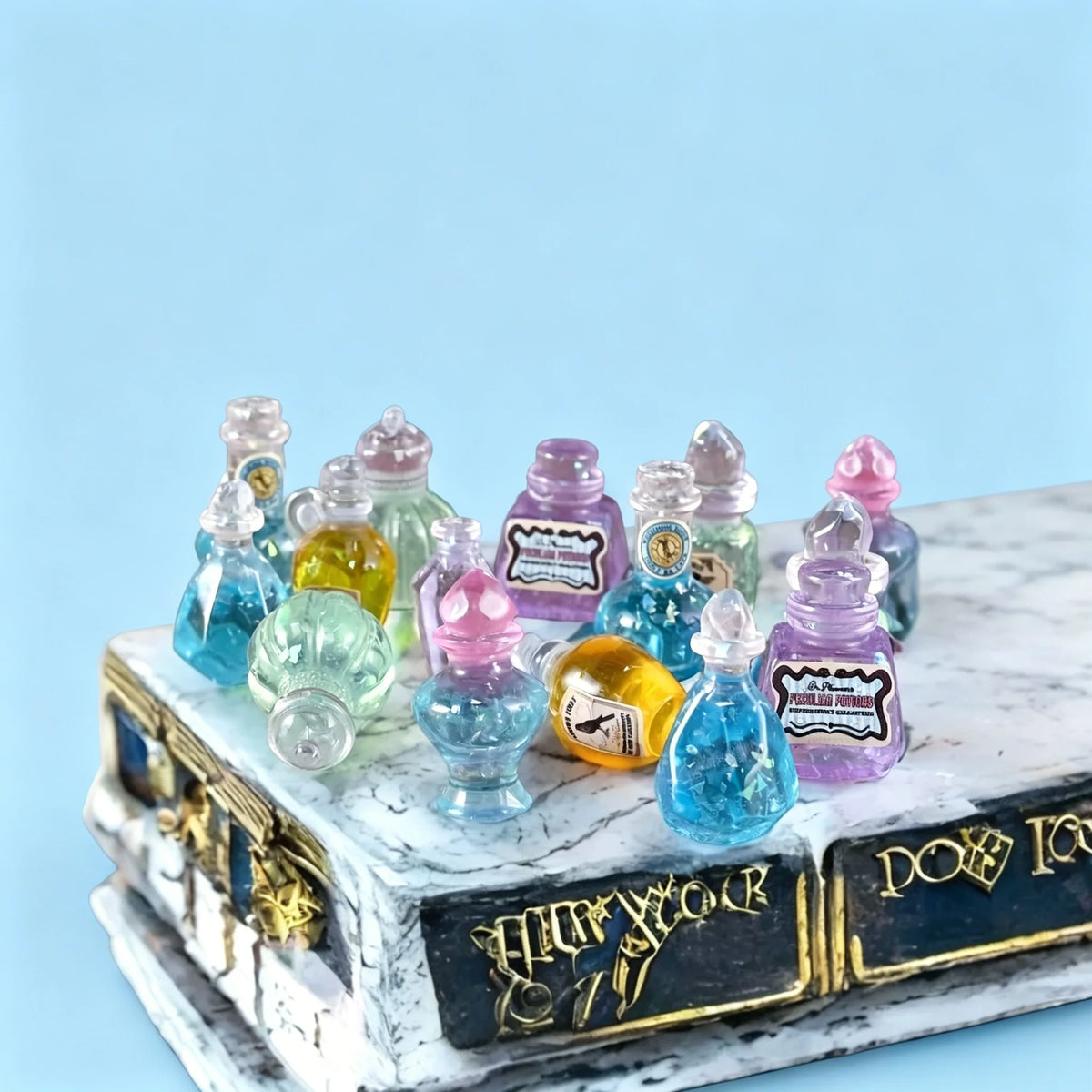A collection of miniature resin magic potion bottles in various colors arranged on a white marble box.