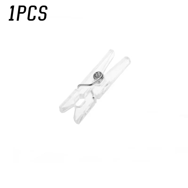 A single mini clear plastic spring clip used for holding photos, papers, and crafts.