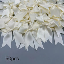 A collection of 50 ivory or cream satin ribbon bows and ties for gift wrapping and decoration.