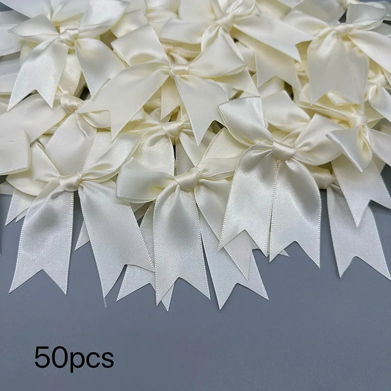 A collection of 50 ivory or cream satin ribbon bows and ties for gift wrapping and decoration.
