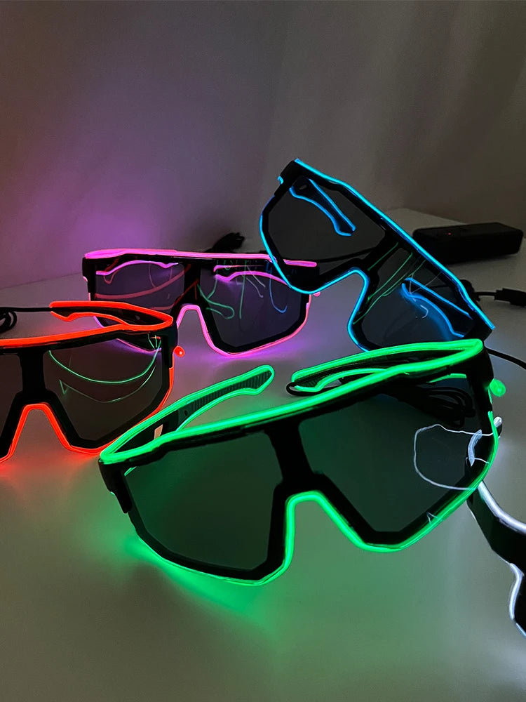 A pair of black party glasses with neon green and pink EL wire accents resting on a white surface.