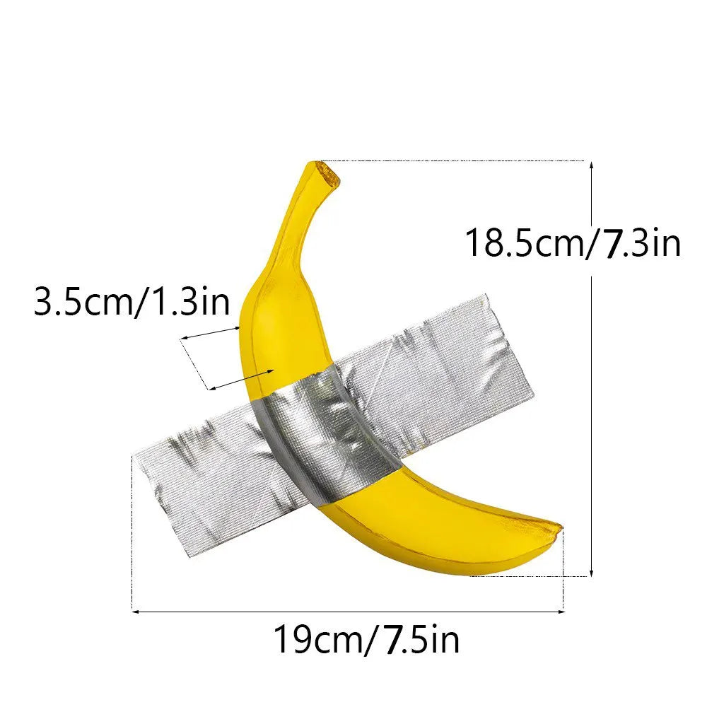 A yellow resin banana wall sculpture with a silver ribbon detail, shown from above.