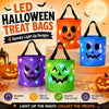 Four spooky LED light-up Halloween treat bags in orange, blue, and green sitting on a surface.