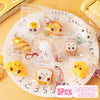 A plate filled with five yellow and white cartoon food squeeze toys or keychains.
