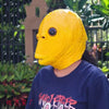 A person wearing a realistic yellow monster mask outdoors.