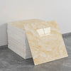 A rectangular sheet of light beige marble tile sticker placed next to a stack of white tiles on a gray floor.