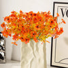 A bouquet of vibrant orange and yellow silk flowers displayed in a white fabric bag.