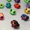 A collection of 3D printed frog car ornaments featuring various colors and color-shifting eyes.