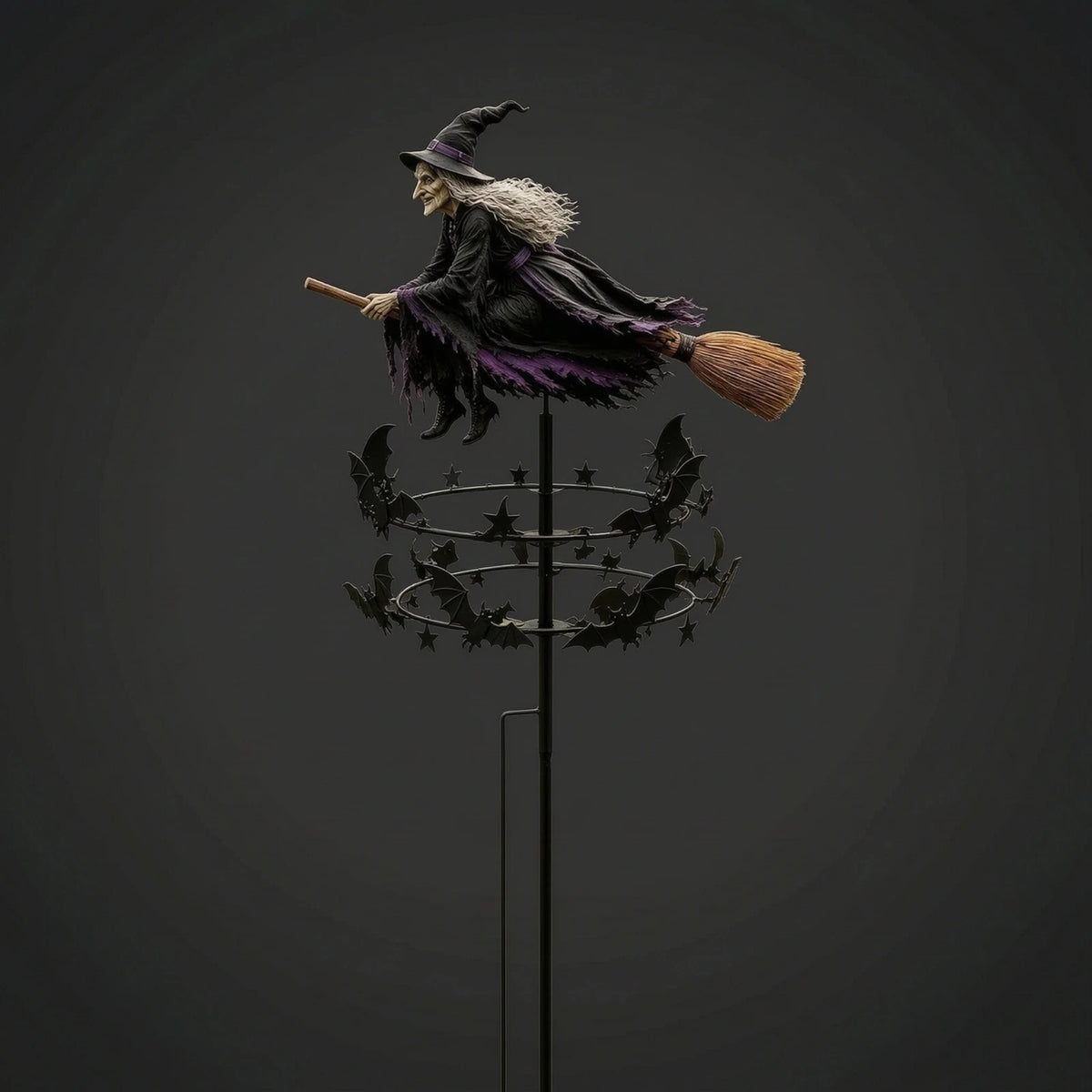 A witch figure in a dark cloak and pointed hat stands atop a rod with a broom, surrounded by black bats.
