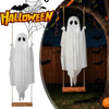 A white ghost decoration hangs from a tree branch in an outdoor Halloween setting.